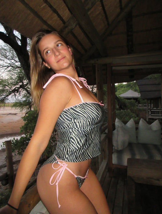 Zed, a stunning zebra print tankini, is the perfect blend of style and comfort! This eye-catching two-piece features adjustable baby pink spaghetti straps that provide a customizable fit, ensuring you feel confident and secure while enjoying the sun. The playful zebra print adds a bold statement to your beachwear collection, while the delicate lace trim offers a touch of femininity. A dainty front bow enhances the charm of this tankini, making it not just a swimsuit but a fashionable piece that stands out!