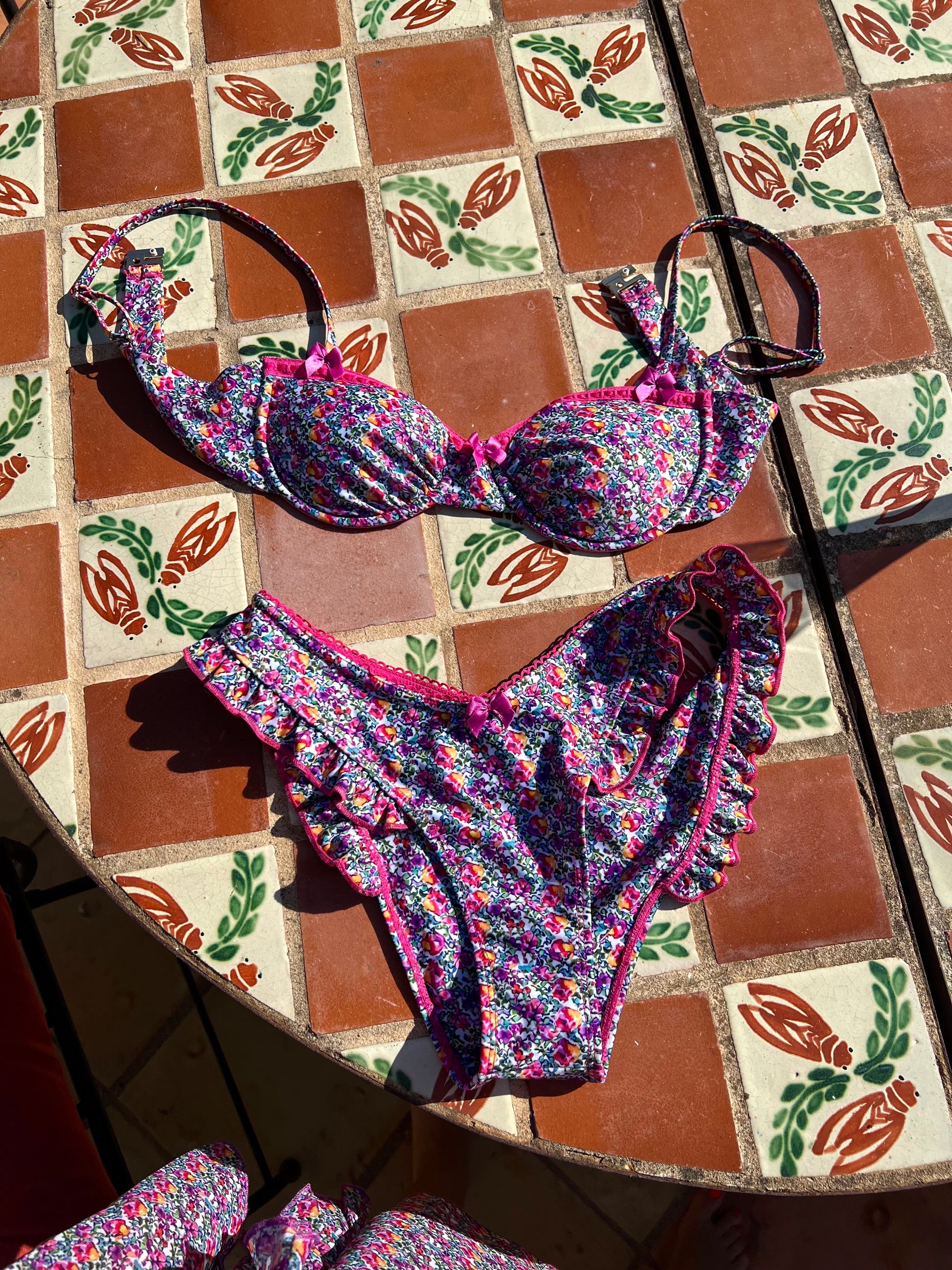 The Saint Tropez Bikini, where sweet style meets undeniable charm. This delightful bikini features dreamy pink and purple florals that pop against a fresh backdrop, creating a vibrant look perfect for summer. Accented with playful pink lace and bow details, it exudes confidence and chic appeal. Designed for comfort and cuteness, this bikini is ideal for beach days or poolside lounging. Embrace your playful side and make a statement with The Saint Tropez Bikini, your go-to for sunny adventures!