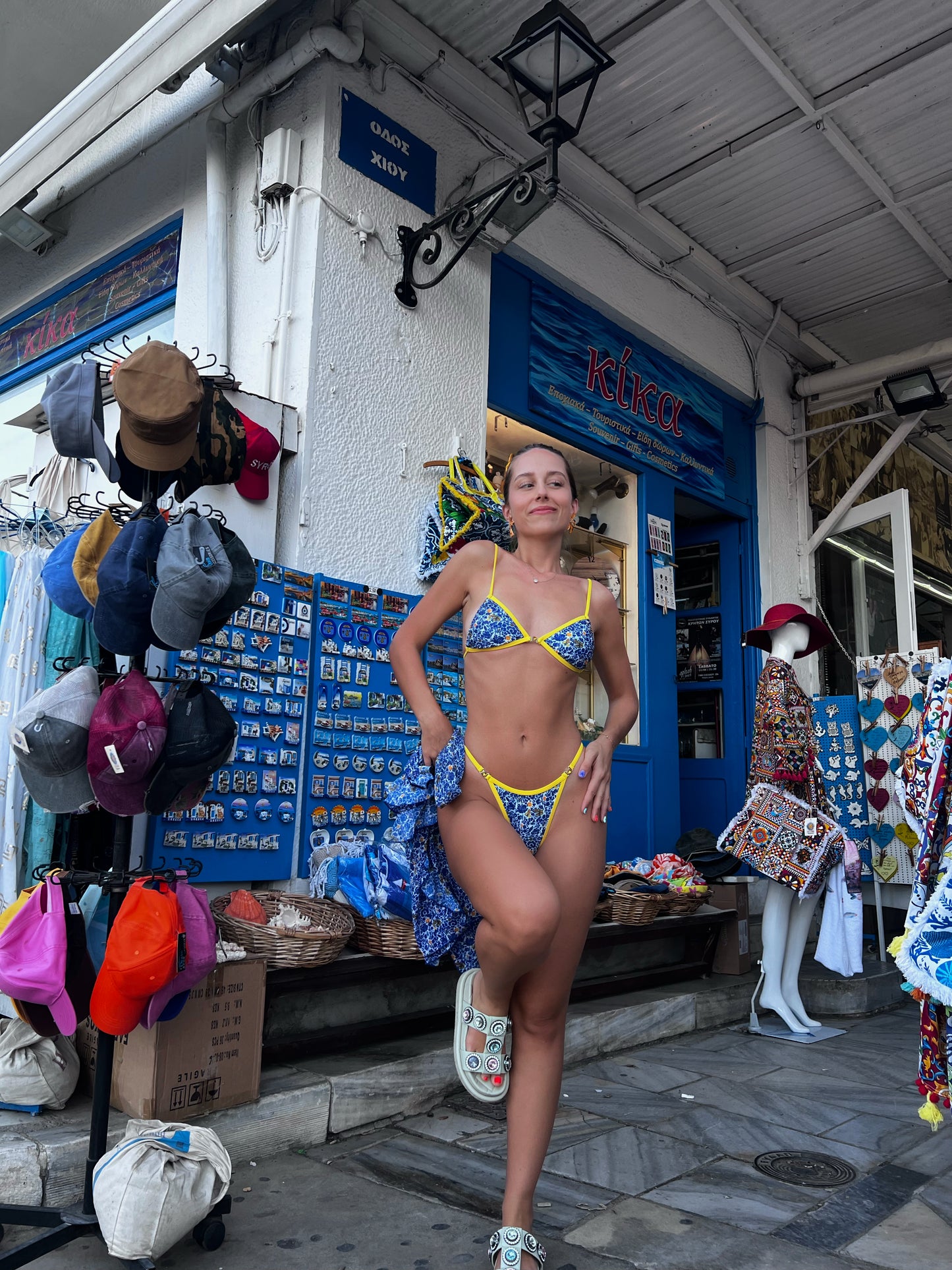 The Ophelia Bikini, a stunning statement piece that radiates vibrant energy. Featuring a classic blend of Mediterranean blue, vibrant yellow, and crisp white, this bikini is adorned with a bold floral print that evokes the beauty of Greece. The eye-catching yellow gemstone accents and matching straps add a touch of elegance. With its flattering fit and stylish design, this bikini is perfect for making a splash at the beach or pool this summer!