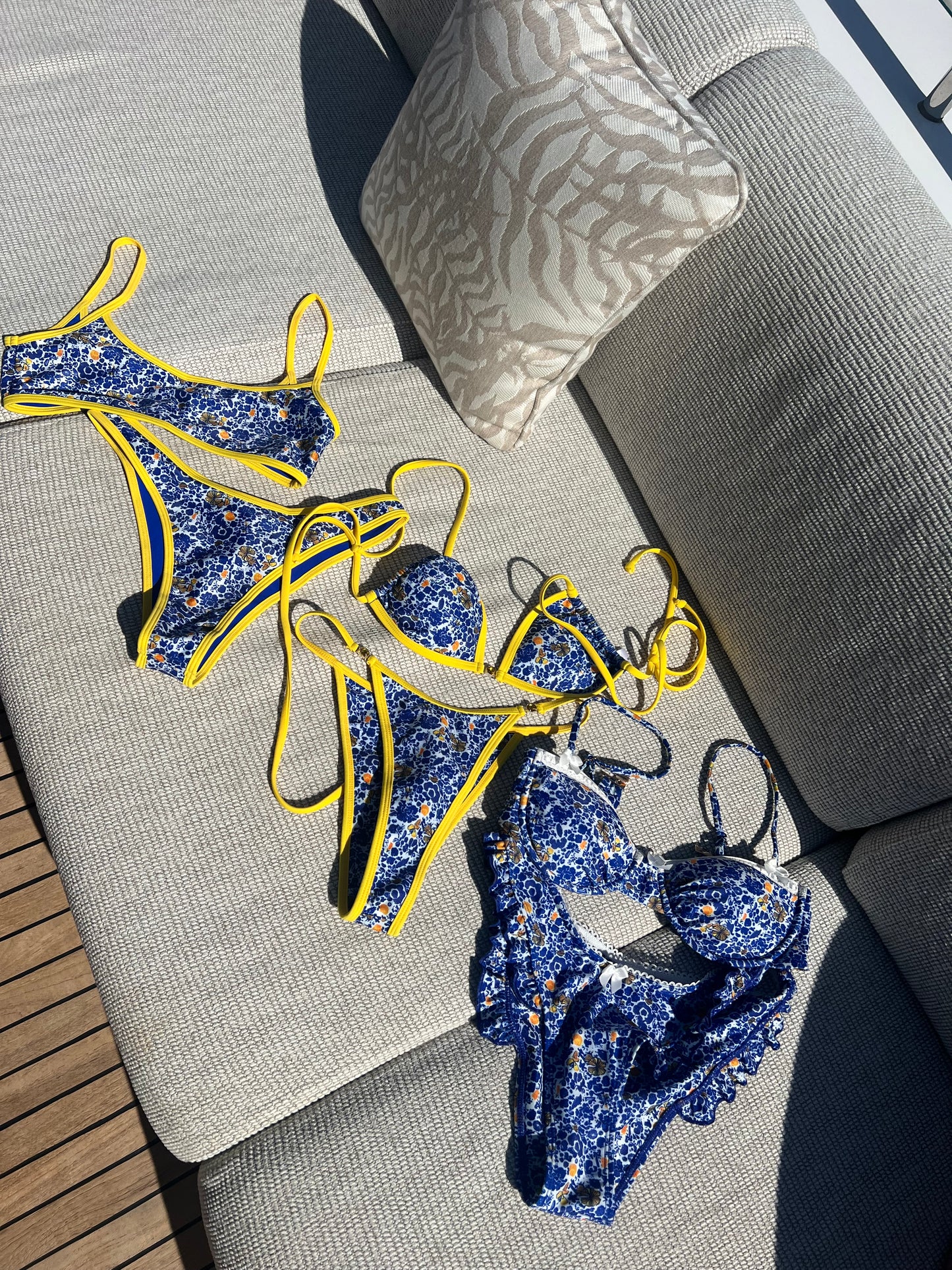 The Ophelia Bikini, a stunning statement piece that radiates vibrant energy. Featuring a classic blend of Mediterranean blue, vibrant yellow, and crisp white, this bikini is adorned with a bold floral print that evokes the beauty of Greece. The eye-catching yellow gemstone accents and matching straps add a touch of elegance. With its flattering fit and stylish design, this bikini is perfect for making a splash at the beach or pool this summer!