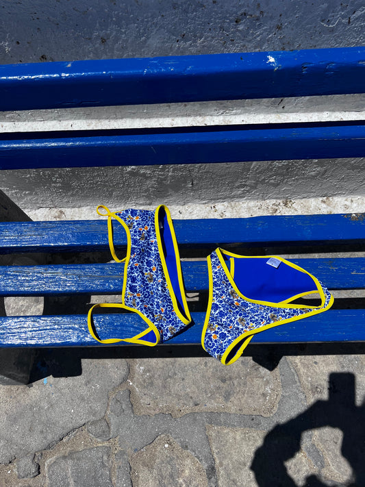 The Athena Bikini, a stunning reversible design that offers two fabulous looks in one. Featuring a white base with vibrant blue and yellow blooms, it reverses to a solid cobalt with cheerful yellow trim for added versatility. This bikini combines practicality and beauty with a sporty fit that flatters your figure. Perfect for beach days or poolside lounging, the Athena Bikini is your go-to choice for a stylish and functional summer wardrobe!