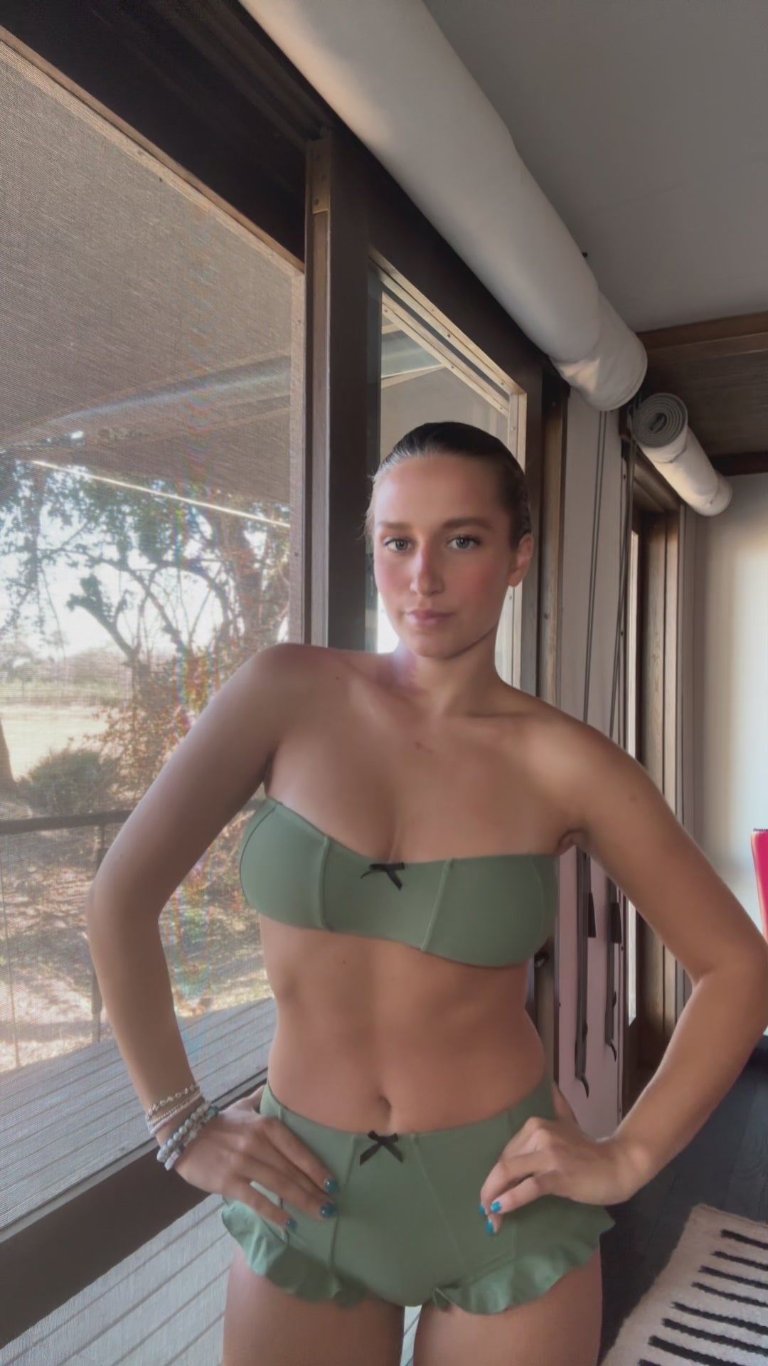 The Rosemary Bikini, a vintage-inspired swimwear piece with a modern twist. This beautiful sage green bikini features charming bow details that add a playful touch while remaining neutral and flattering. The bandeau top showcases a minimalist tie-back design for a comfortable fit, while the high-waisted bottoms feature elegant ruffle detailing, enhancing your silhouette. Versatile and stylish, the Rosemary Bikini is perfect for making a statement at the beach or pool!