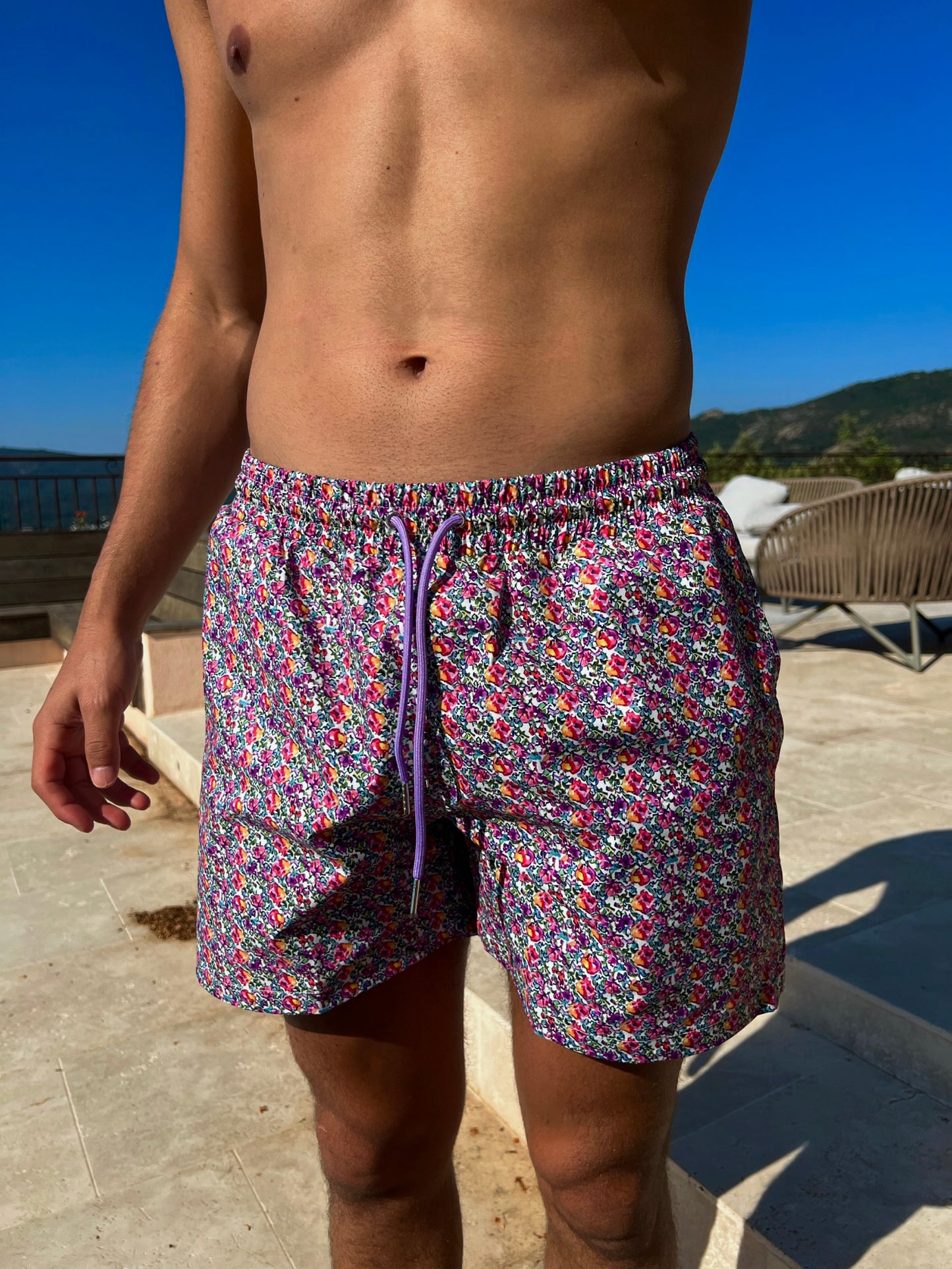 The Saint Tropez Short, the ultimate men's swim shorts that blend functionality and fashion. Featuring a vibrant floral print in purple and pink, these shorts embody effortless tropical vibes. Designed for comfort, they include a convenient string tie for a secure fit and functional pockets for your essentials. Versatile enough for beach days or pool parties, The Saint Tropez Short is a stylish choice that ensures you stand out while enjoying the sun!