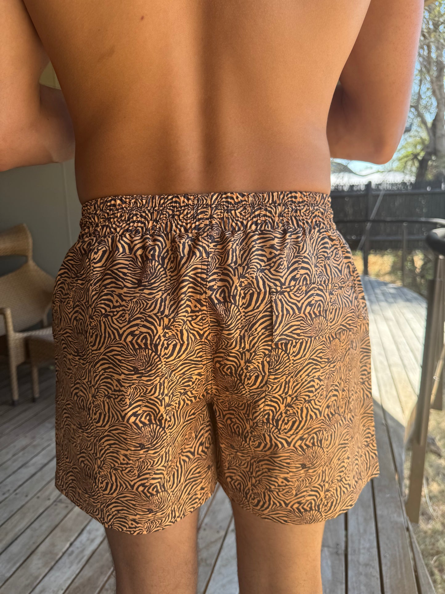 A close-up image of the back of the tiger print swim shorts showcases their stylish design and fit. The vibrant pattern continues seamlessly, while the shorts feature a comfortable waistband that provides a secure fit. The back view highlights the shorts' versatility, making them suitable for both beach activities and casual outings. This detail emphasizes the quality of the fabric and stitching, showcasing a blend of fashion and functionality perfect for summer adventures.