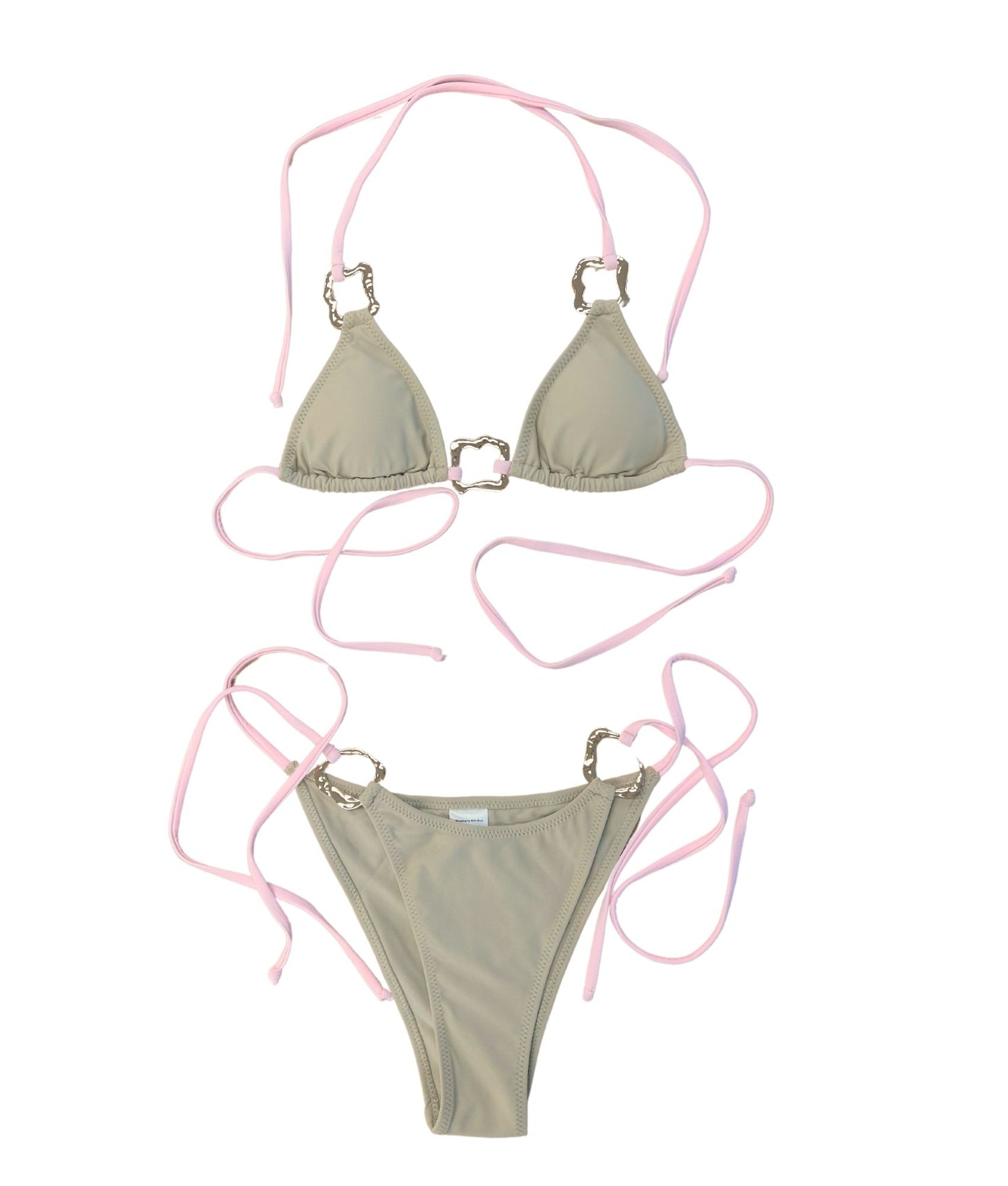 The Safari Bikini, a chic and trendy swimwear piece featuring a stylish beige and tan color with delicate baby pink string ties. Accented with luxurious gold square hardware details, this bikini offers a flirty yet functional design that is effortlessly neutral and easy to mix and match. The supportive top ensures comfort while enhancing your silhouette, making it perfect for any beach day. Flaunt your stripes and embrace a luxe, delicate look with The Safari Bikini this summer!