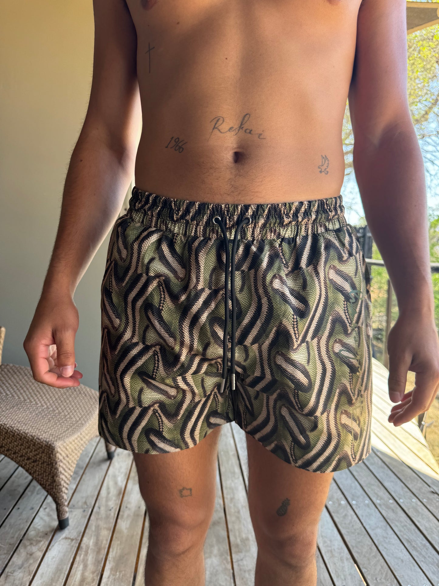 The Mamba Short, stylish men's swim trunks featuring a bold snake print design that stands out in any setting. Perfect for both swimming and streetwear, these shorts offer maximum freedom of movement and a sleek fit for all-day comfort. Crafted from high-quality materials, they are designed to keep you looking sharp whether you're at the beach or out on the town. Embrace your adventurous spirit with The Mamba Short, where style meets practicality for every summer adventure!