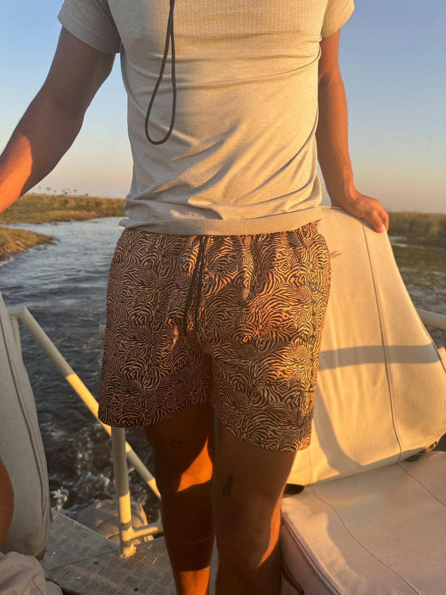 A photo features a male model outdoors, showcasing his tiger print swim shorts. The vibrant pattern stands out against the backdrop of his vacation in South Africa. His confident pose captures the fun and adventurous spirit of summer, making the versatile shorts an ideal choice for various activities.