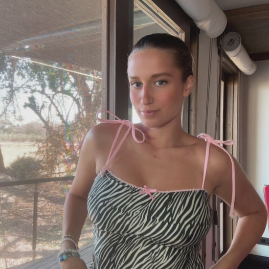 Zed, a stunning zebra print tankini, is the perfect blend of style and comfort! This eye-catching two-piece features adjustable baby pink spaghetti straps that provide a customizable fit, ensuring you feel confident and secure while enjoying the sun. The playful zebra print adds a bold statement to your beachwear collection, while the delicate lace trim offers a touch of femininity. A dainty front bow enhances the charm of this tankini, making it not just a swimsuit but a fashionable piece that stands out!